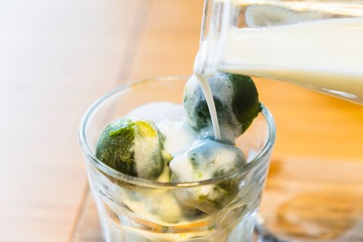 matcha ice cream and fresh milk in glass on wooden table