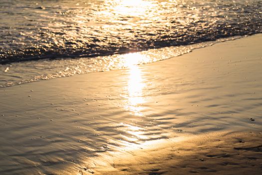 soft wave on the beach with gold lighting in the morning