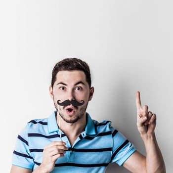 Portrait of man with fake mustache on stick saying something important with finger up