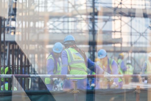 Construction site with team of construction laborers working on scaffold.