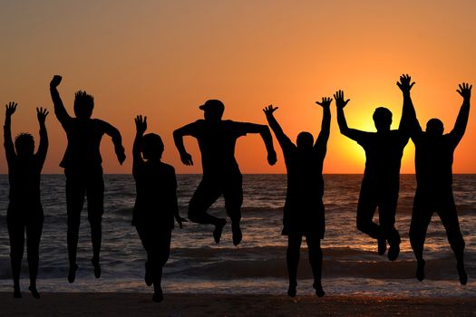 Group of silhouettes of people jumping on beach