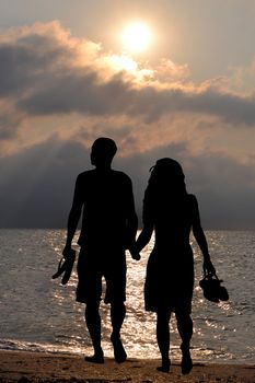 Romantic lovers walking on the beach at sunrise,