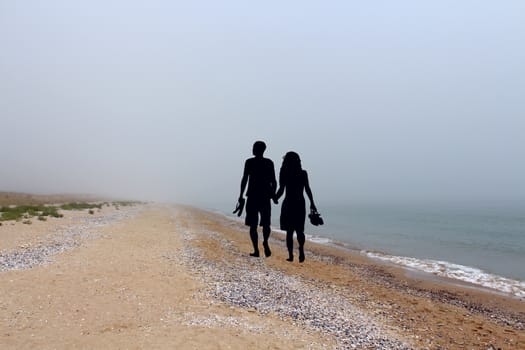 Romantic couple silhouette walking on the beach