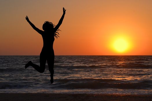Woman silhouette jumping and enjoy sunrise