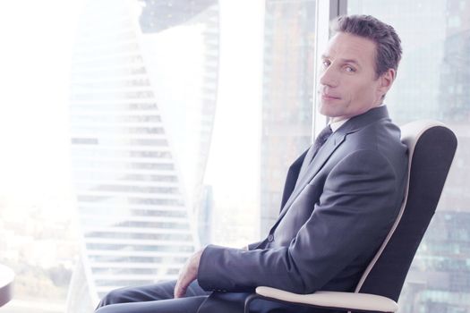 Portrait of a business man sitting on armchair against the window