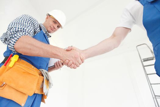 Workers shaking hands finishing construction or renovation deal