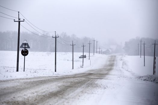 Snowfall and sleet on winter road. Ice snowy road. Winter snowstorm. Black ice and blizzard.