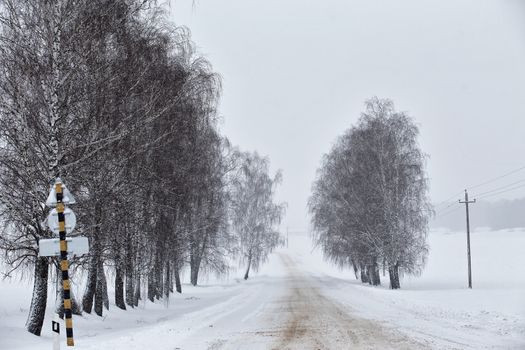 Snowfall and sleet on winter road. Ice snowy road. Winter snowstorm. Black ice and blizzard.