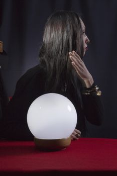 Fortune teller with a magic ball on a black background