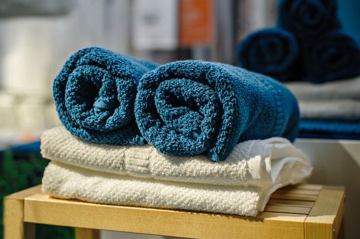 Four clean soft double bath towels set of different colors stacked, lying on wooden chair. Side view closeup