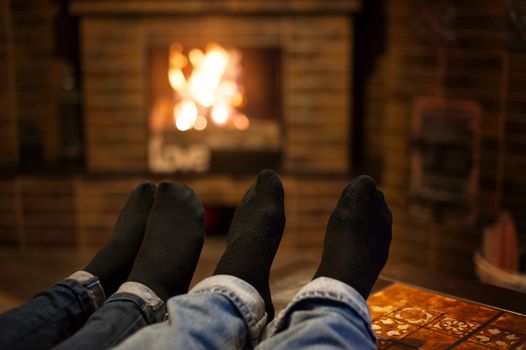 Close up of romantic legs in socks in front of fireplace.