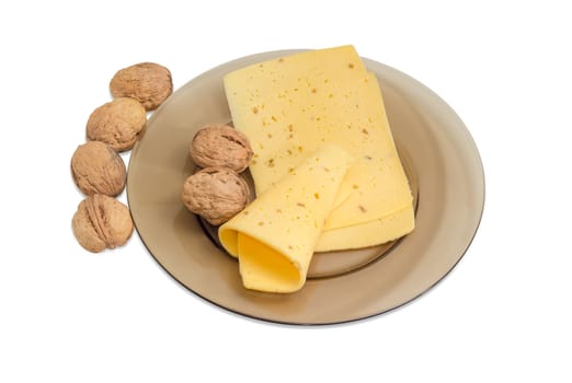 Several slices of a semi-hard cheese made with pounded walnuts on a glass dish and several whole walnuts on a light background

