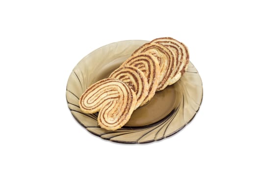 Several flaky cookies in a palm leaf shape, made from puff pastry with chocolate filling on a glass saucer on a light background
