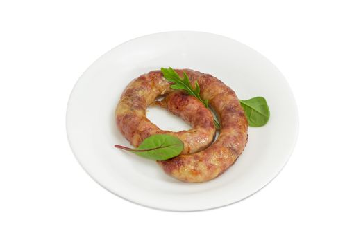 Freshly roasted pork sausage in natural casing with few leaves of different greens on a white dish on a light background
