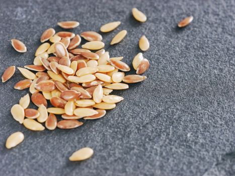 Golden and brown flax seed on gray slate background with copy space