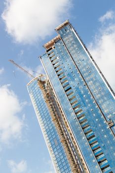 Huge skyscrappers construction site with cranes on top of buildings. Rapid urban and construction sector development or inflation of real estate bubble.