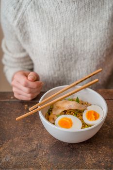 Woman behind the table and the Asian soup Ramen vertical