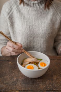Woman behind the table and the Asian soup Ramen vertical