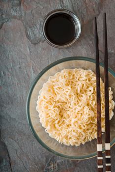 Soup Ramen noodles in glass bowl and sause on tte gray table vertical