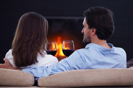 Romantic couple drinking wine at home near fireplace