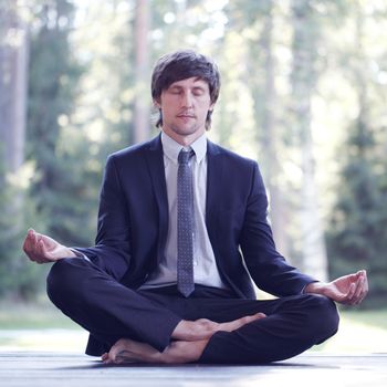 Businessman in suit practicing yoga in park