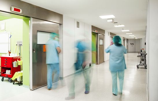 Blurred figures of doctors and nurse down the corridor in surgery section of a modern hospital.