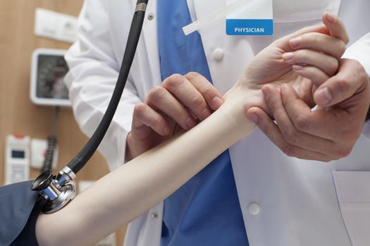 Close-up of a doctor hands measuring the pulse of a patient in hospital.