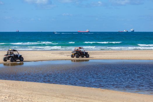 People ride ATV along the sea shore