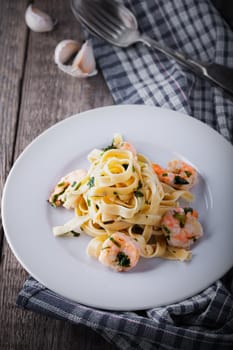 Tagliatelle with shrimps placed on a wooden surface
