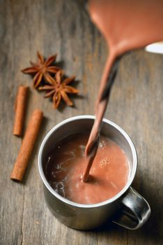 Hot chocolate with cinnamon stick on wooden table