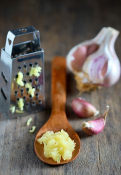 Garlic in spoon on wooden background