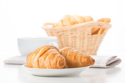 Fresh baked croissants served with coffee and a newspaper.