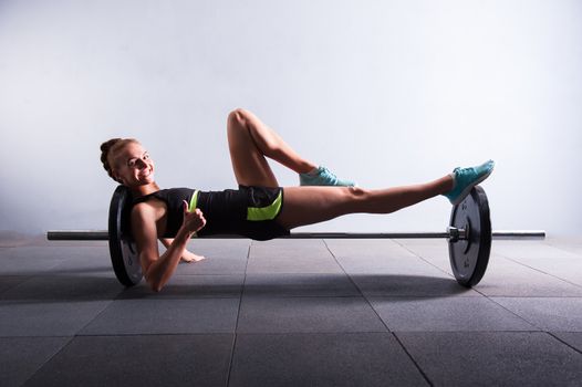 Young woman bench pressing weights at gym, low key