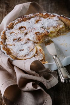 Apple pie with the knife on wooden table
