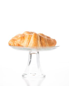 Fresh made buttery croissants on a glass stand.