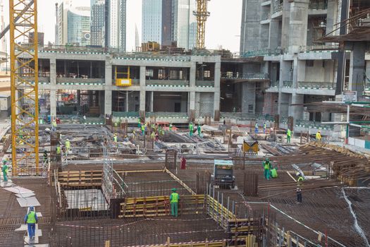 Laborers working on modern constraction site works in Dubai. Fast urban development consept.