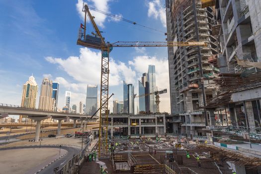 Laborers working on modern constraction site works in Dubai. Fast urban development consept.