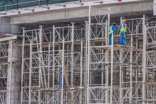 Construction site with team of construction laborers working on scaffold.