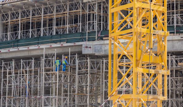 Construction site with team of construction laborers working on scaffold.