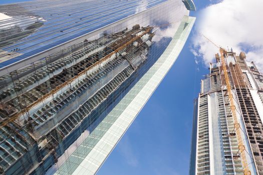 Huge skyscrappers construction site with cranes on top of buildings. Rapid urban and construction sector development or inflation of real estate bubble.