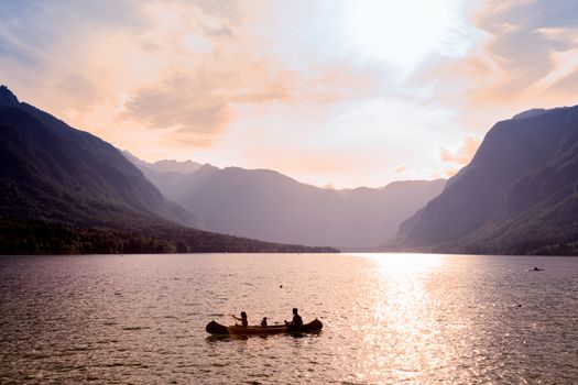Family rowing in canoe boat on beautiful lake Bohinj at sunset, located in the Bohinj valley of Julian Alpsin in Triglav national park, Slovenia.