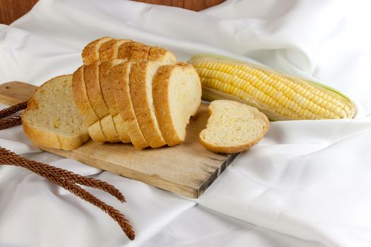 bread made from corn on the white fabric. Slices of corn bread laying on a chopping Board and Sweet corn cobs