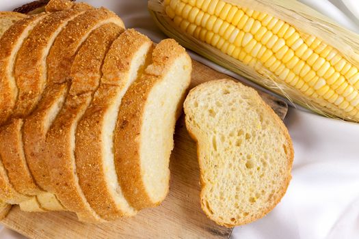 bread made from corn on the white fabric. Slices of corn bread laying on a chopping Board and Sweet corn cobs