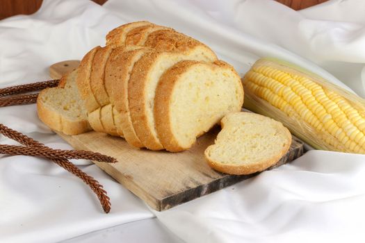 bread made from corn on the white fabric. Slices of corn bread laying on a chopping Board and Sweet corn cobs