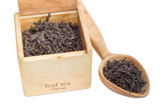 Large leaf of black tea in a wooden box and wooden spoon on a light background closeup
