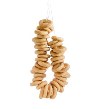 Hanging on a string a bunch of small round bagels on a light background 
