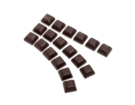 Square pieces of dark chocolate laid out in three rows on a light background
