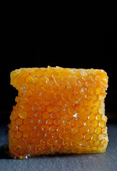 Honeycomb and honey on black plate