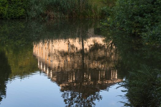 Reflection of a building in the water surface of a small pond.