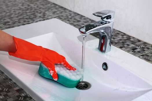 hand of woman in glove who washes white sink